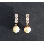 A pair of pearl and diamond earrings, set with three round old cut diamonds above a suspended pearl,