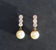 A pair of pearl and diamond earrings, set with three round old cut diamonds above a suspended pearl,