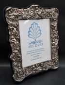A large silver plated photograph frame, profusely decorated with cherubs, leaves and flowers,