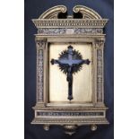 A bronze crucifix depicting Jesus on the cross, in an elaborate gilt frame with an arched pediment,