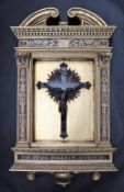 A bronze crucifix depicting Jesus on the cross, in an elaborate gilt frame with an arched pediment,