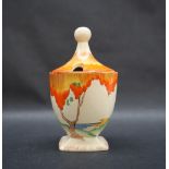 A Clarice Cliff preserve pot and cover, painted with an orange tree and coastal landscape beyond,