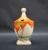 A Clarice Cliff preserve pot and cover, painted with an orange tree and coastal landscape beyond,