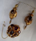 A Victorian yellow metal garnet set brooch and earrings set, of scrolling form,