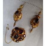 A Victorian yellow metal garnet set brooch and earrings set, of scrolling form,