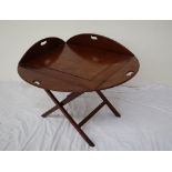 A George III style mahogany butlers tray with drop flaps and cut out handles on a folding stand