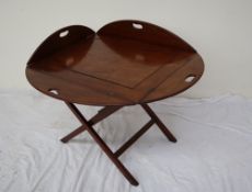 A George III style mahogany butlers tray with drop flaps and cut out handles on a folding stand