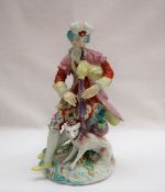 A Derby porcelain figure seated playing bagpipes with a dog at his feet on a circular base, 19.