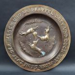 A bronze plaque of circular form, decorated to the centre with three hares and thistles,