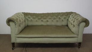 A Victorian drop arm Chesterfield settee on turned legs and casters,