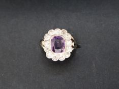 An amethyst and diamond cluster ring, the central oval faceted amethyst 9mm x 8mm,