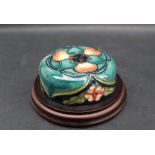 A Moorcroft pottery lid, decorated with flowers and buds to a green ground,