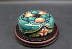 A Moorcroft pottery lid, decorated with flowers and buds to a green ground,