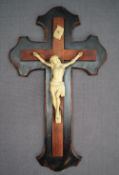 A Crucifix, with a cream painted metal on a stained treen backing, 39.