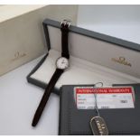 A lady's Omega De Ville wristwatch, the white dial with Roman numerals, on a leather strap,