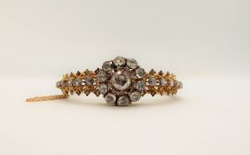 A Victorian diamond encrusted hinged bangle, set with rose cut diamonds to a yellow metal setting,