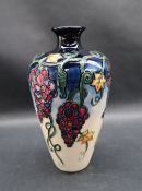 A Moorcroft pottery vase decorated with bunches of grapes and leaves to a cream ground,