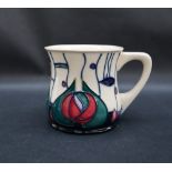 A Moorcroft pottery mug, decorated with pink and green flowerheads to a cream ground,