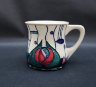 A Moorcroft pottery mug, decorated with pink and green flowerheads to a cream ground,