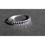 An 18ct white gold sapphire and diamond hinged bangle set with nine oval faceted sapphires and