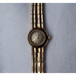 A lady's 9ct yellow gold Omega wristwatch, the circular silvered dial on an integral strap,