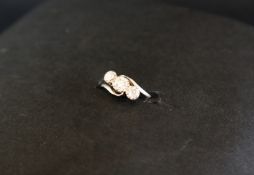 A three stone diamond ring, set with old round cut diamonds to a white metal setting and shank,