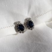 A pair of sapphire and diamond earrings, set with a large oval faceted sapphire,