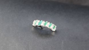 An Emerald and diamond set with six pairs of round brilliant cut diamonds separated by five pointed