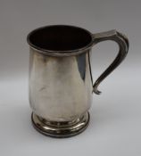 A George V silver tankard of baluster shape with a scrolling handled on a spreading foot,