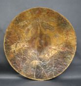 A 20th century copper disk with yellow metal overlay of leaves, indistinctly signed,