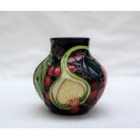 A Moorcroft pottery vase decorated in the fig, grape and peach pattern to a blue ground,