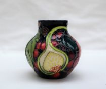 A Moorcroft pottery vase decorated in the fig, grape and peach pattern to a blue ground,