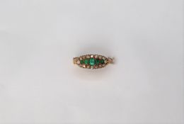 A late Victorian emerald and diamond ring set with five emeralds surround by old cut diamonds to an