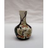 A Moorcroft pottery vase with a thin tapering neck, decorated with cream flowers and leaves,