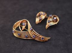 A yellow metal sapphire set brooch and earrings suite, of wave form,