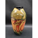 A Moorcroft pottery vase decorated with swaying trees to an orange ground,