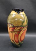 A Moorcroft pottery vase decorated with swaying trees to an orange ground,