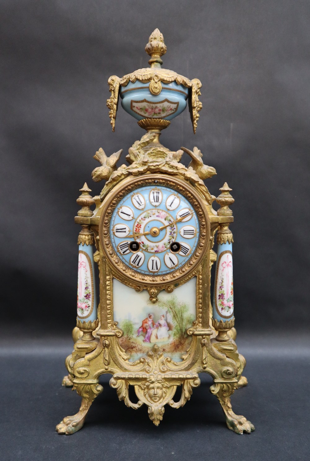 A 19th century French ormolu clock with a porcelain urn surmount,