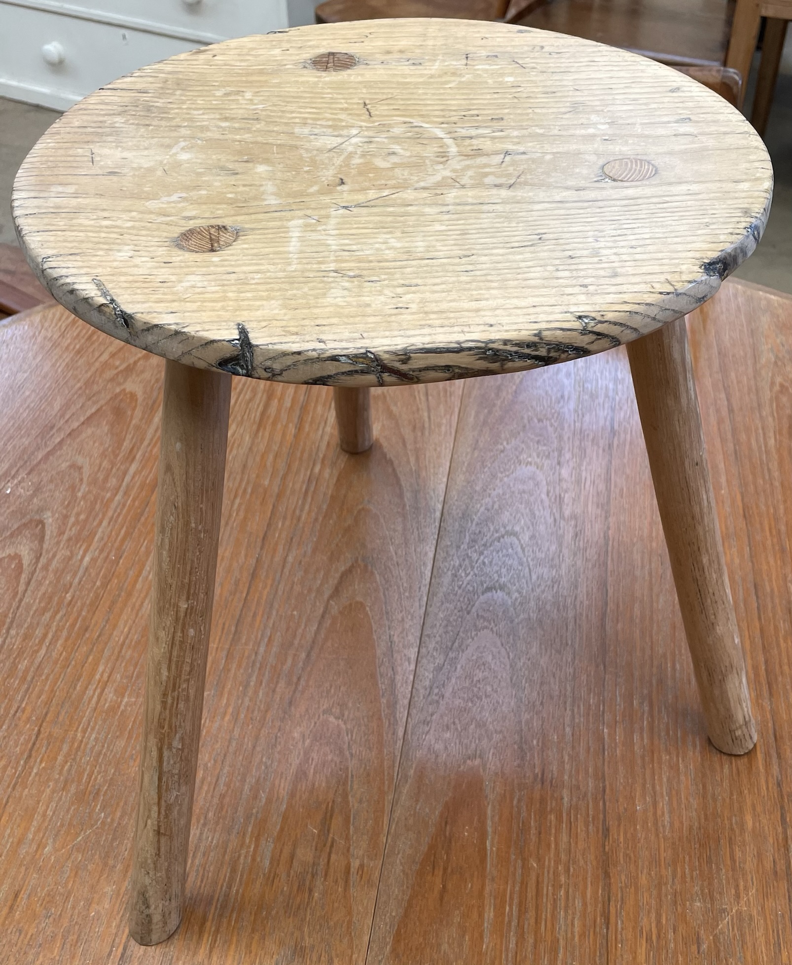 A pine milking stool with a circular top and three legs