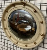 A cream and gilt decorated convex wall mirror of circular form