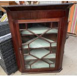 A 19th century mahogany hanging corner cupboard with a moulded cornice and astragal glazed door