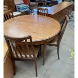 A mid 20th century teak dining suite comprising a circular extending dining table four chairs and a