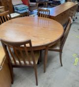 A mid 20th century teak dining suite comprising a circular extending dining table four chairs and a