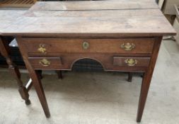 A George III oak lowboy with a planked top above three drawers and an arch on square tapering legs