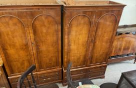 A pair of reproduction yew wood wardrobes, with a moulded cornice and drawers to the base,