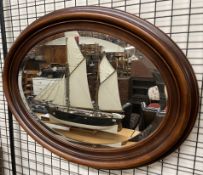 A modern mahogany oval wall mirror