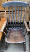 A 19th century slat back kitchen elbow chair with a solid seat on turned legs