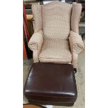 An upholstered wing back elbow chair together with a leather footstool