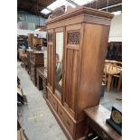 A satin walnut wardrobe, with a carved shaped cornice above a central mirrored panel and two doors,