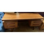 A mid 20th century teak dressing table with a rectangular top above a pull out drawer and two pairs